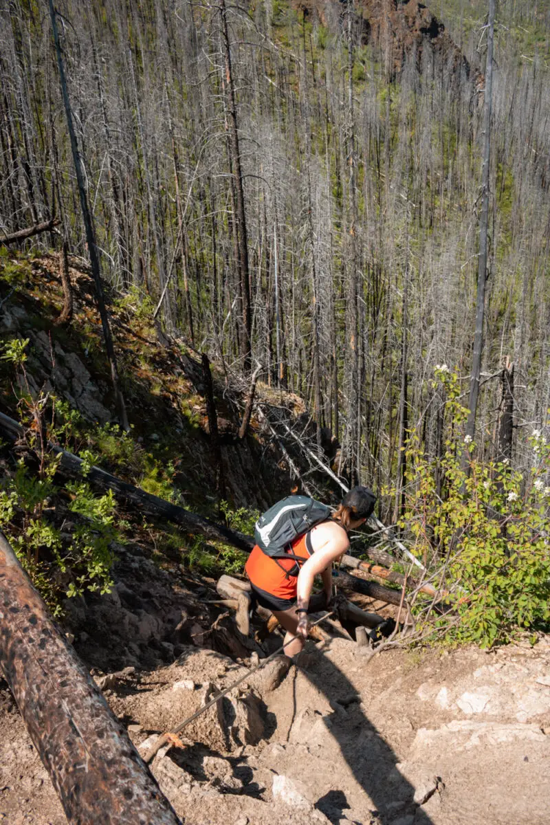 Woman scrambles down the steep trail to Christie Falls with the help of a rope.
