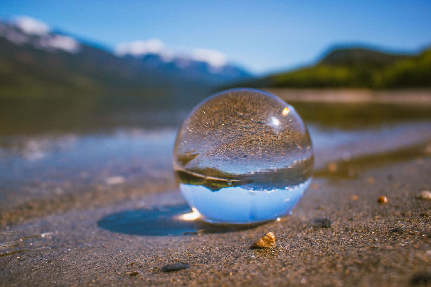 Glass ball in the sand. Image reflected in ball is upside down.