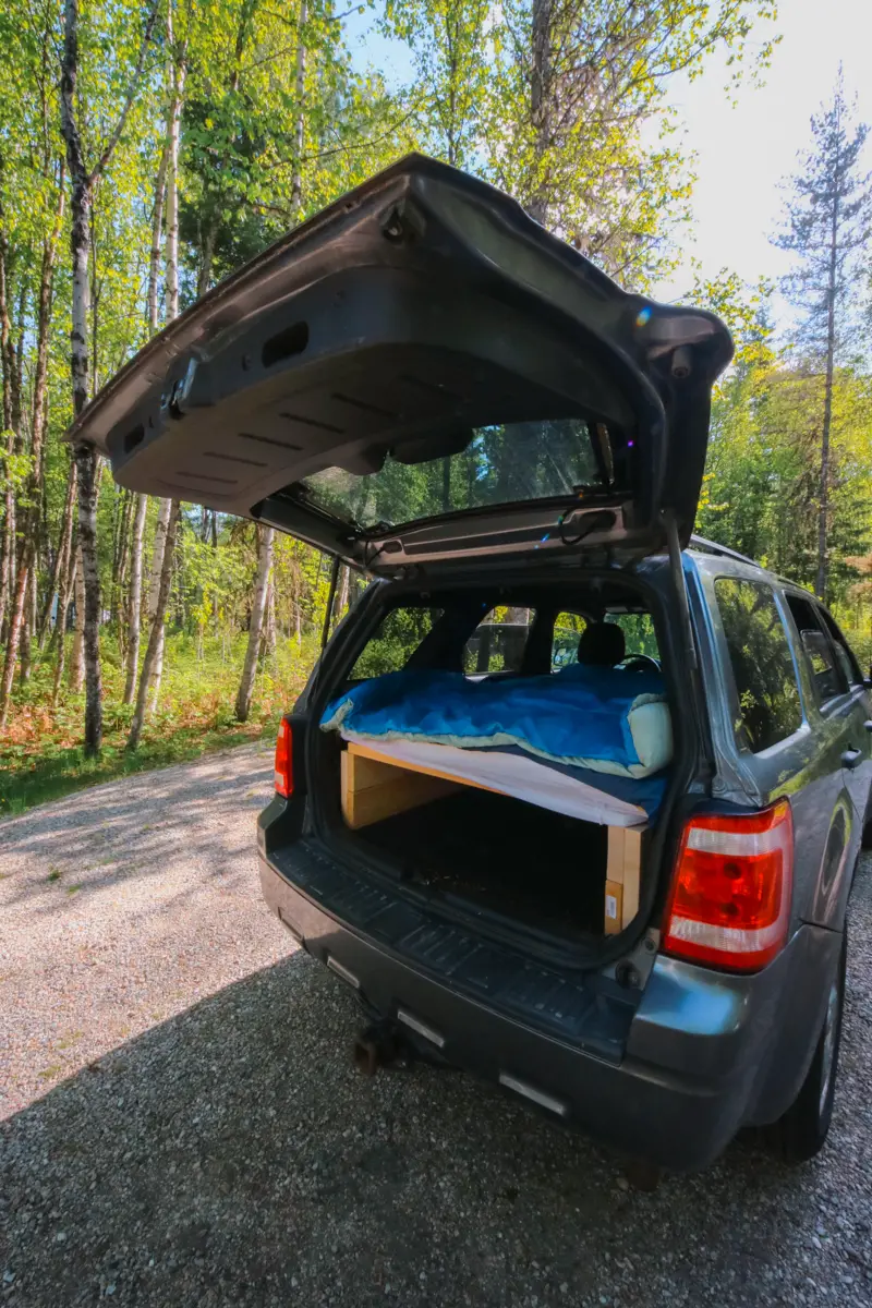 Open hatch on a Ford Escape SUV. The back is converted into a camping setup.