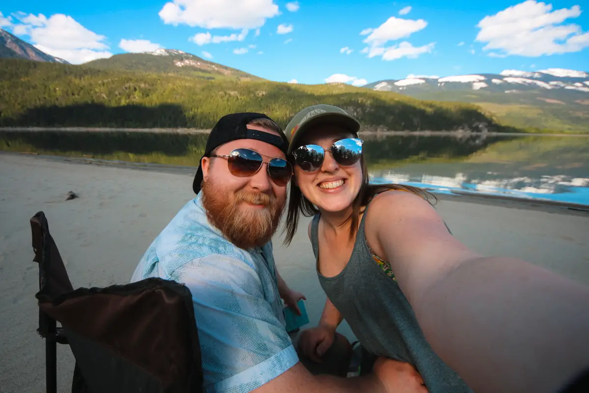 Selfie of a man and woman on a large sandy beach on Arrow lake at Blanket Creek Provincial Park in BC