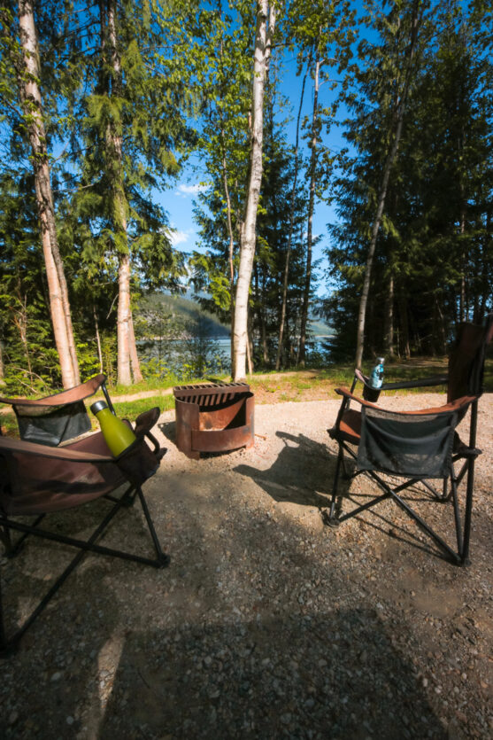 Two chairs around a fire with a lake visible in the background.