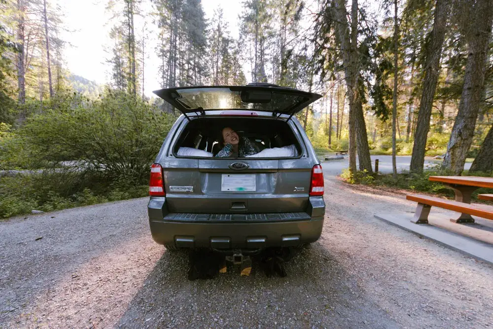 Woman smiling from the back of a Ford Escape camping setup
