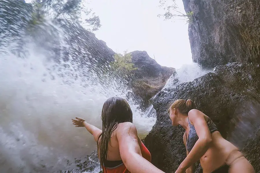 Two woman stand underneath Bear Creek waterfall