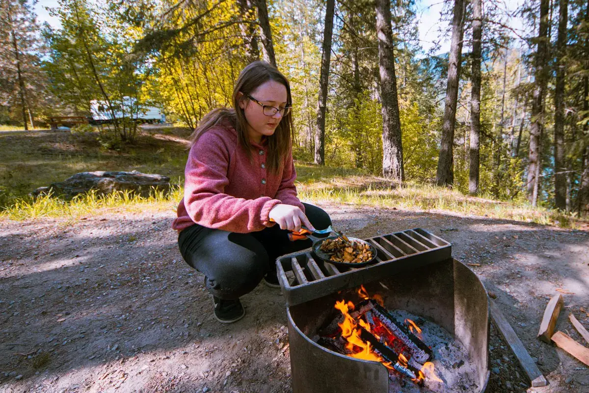 Woman cooks on a firepit at a campsite at Texas Creek campground