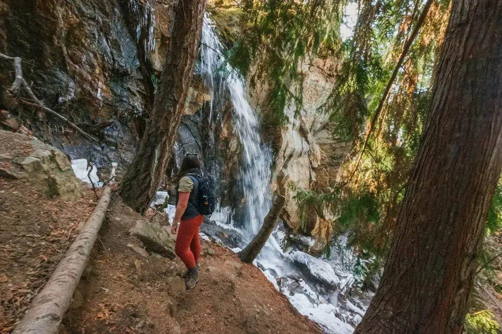 Woman stands in front of a small waterfall in the Okanagan