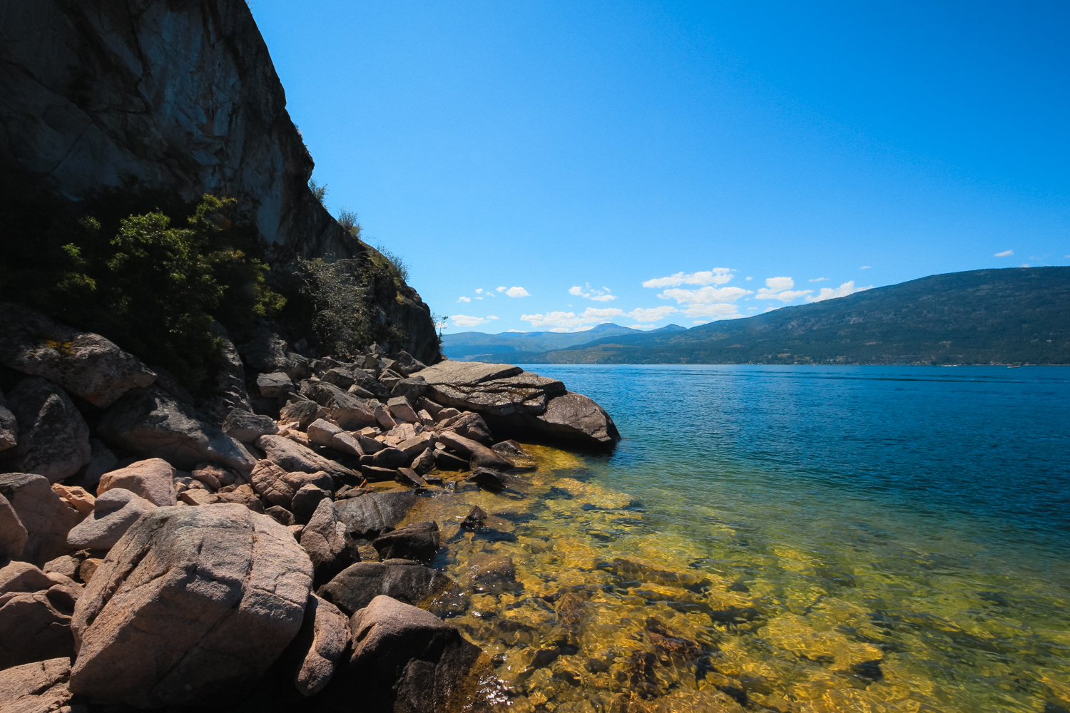 Bright blue and yellow water on the the rocky shoreline of a large lake
