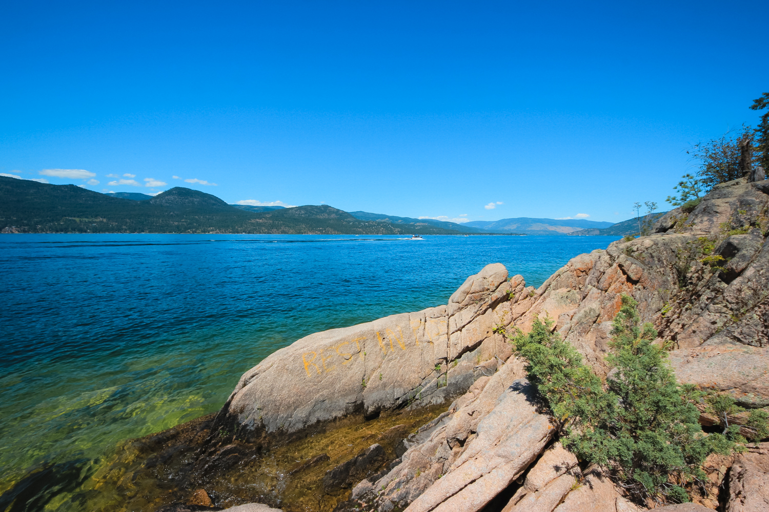 Rocky shorline juts into tropical coloured water on Okanagan Lake