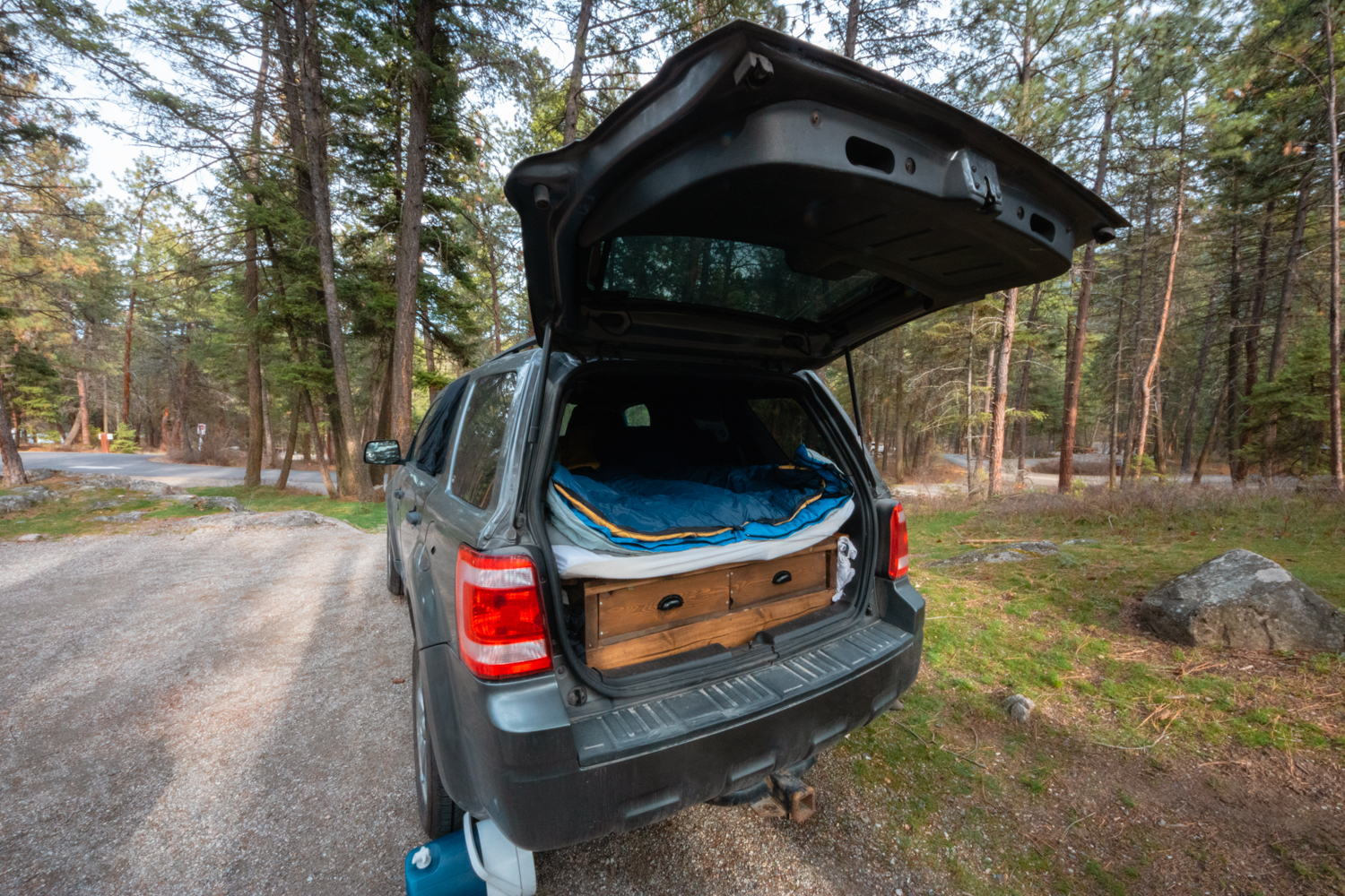 Back hatch of a Ford Escape SUV is open, revealing a camping setup