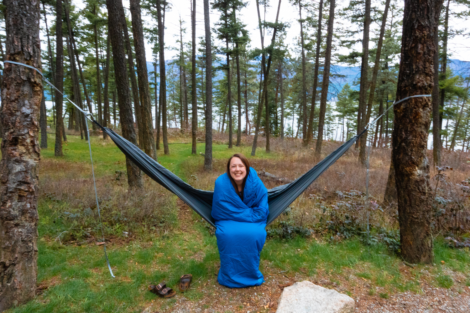 Woman sits on a hammock bundled in a sleeping bag