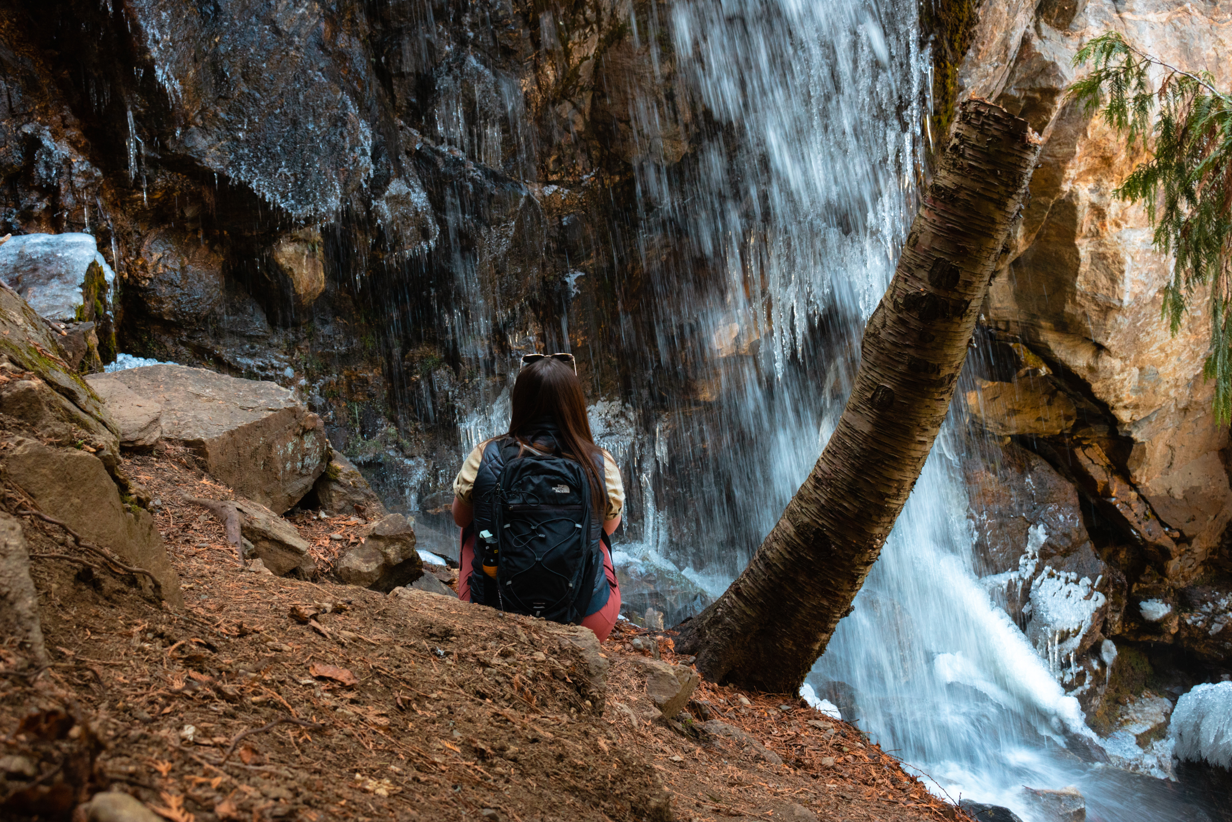 Women sits in front of Cosens Bay waterfall