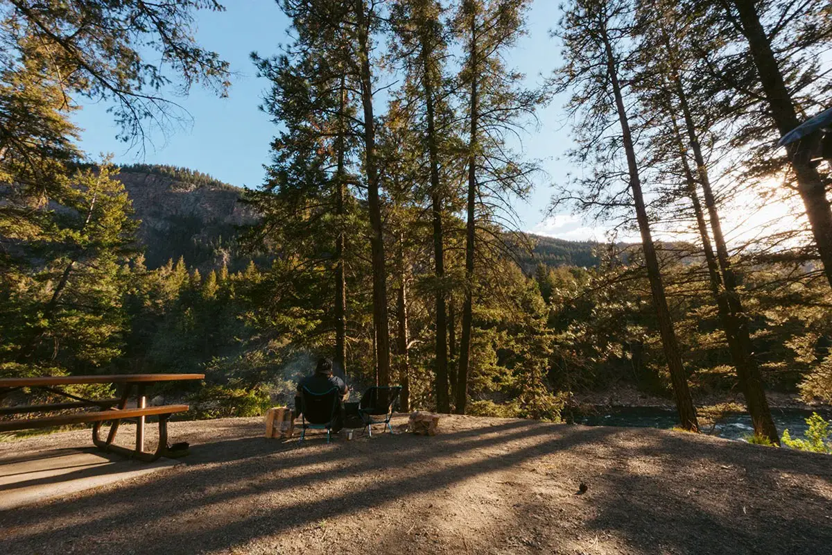Man sitting on camp chairs near the firepit at a campsite on the Similkameen River