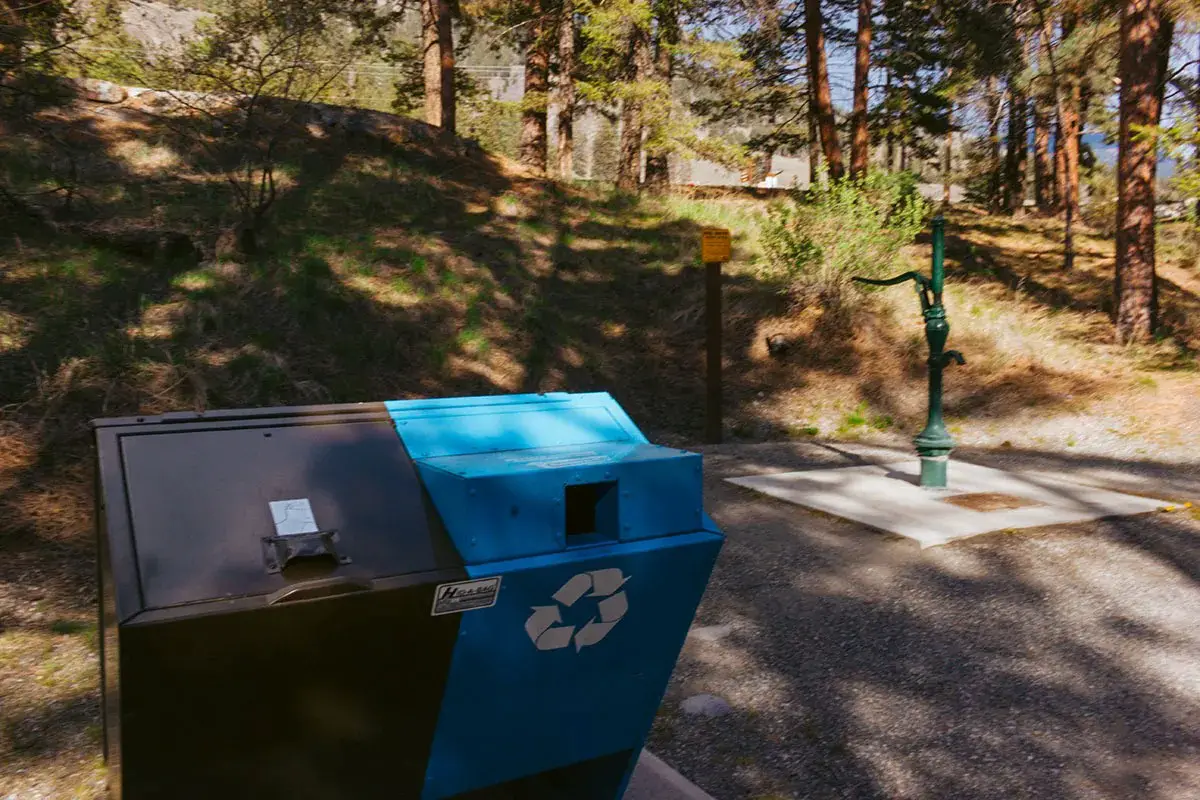Garbage and recycling bins with a water pump in the background