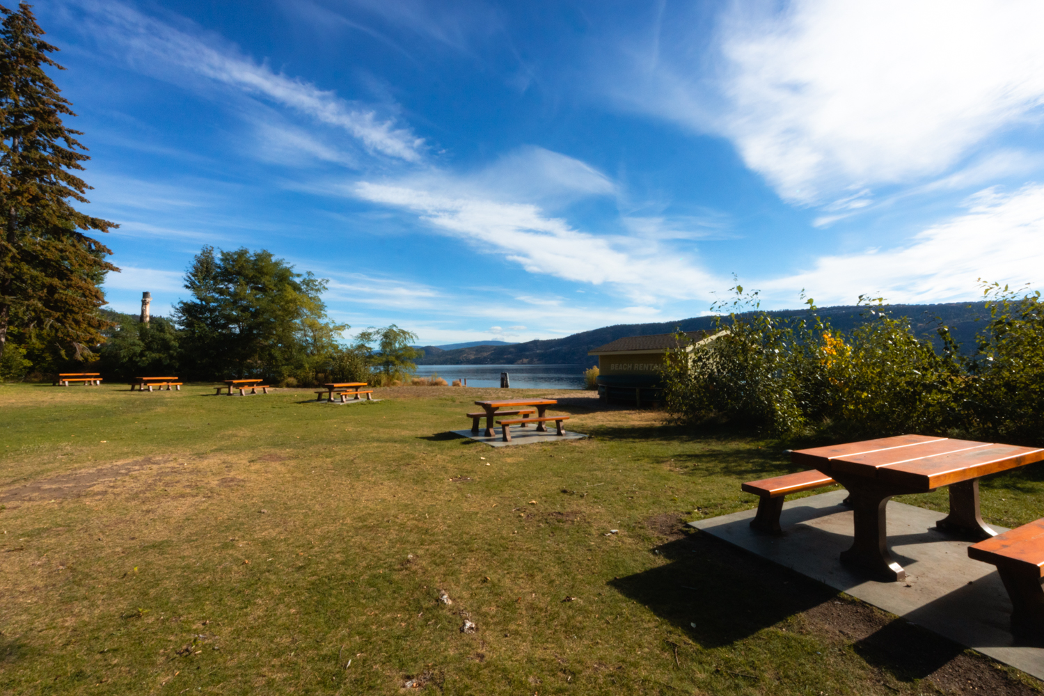 Picnic benches at the day-use area of Bear Creek Provincial park on the shores of Okanagan Lake