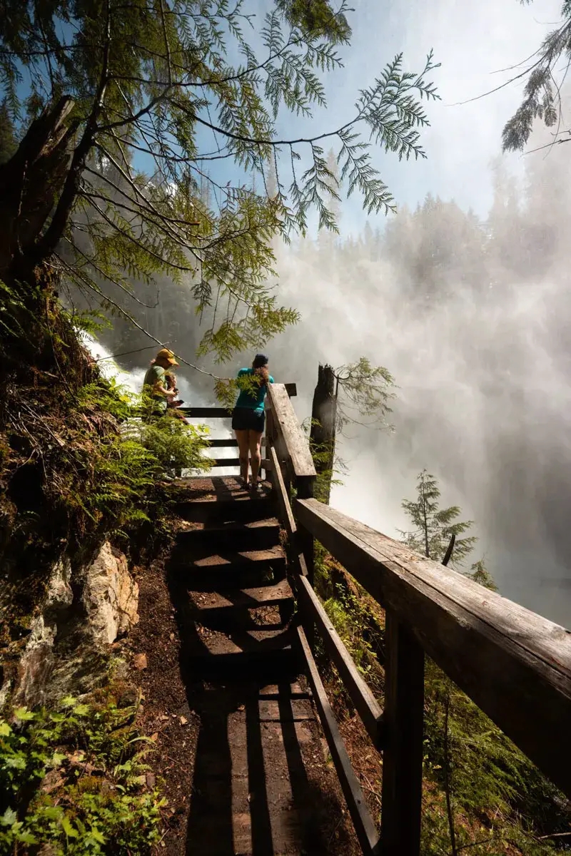 A woman stands at a viewing platform for Rainbow Falls in British Columbia
