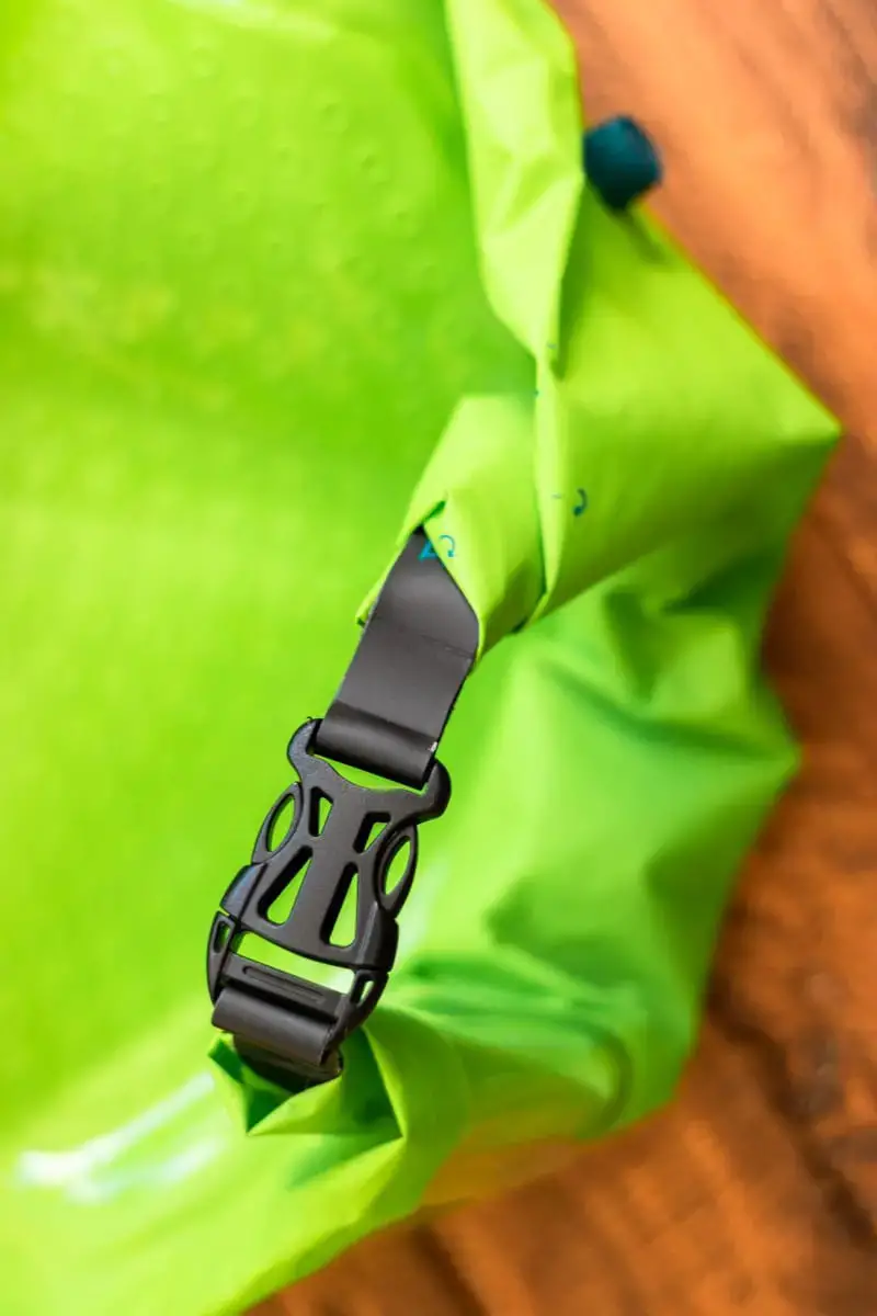 The bright green Scrubba bag is rolled up and clipped shut.