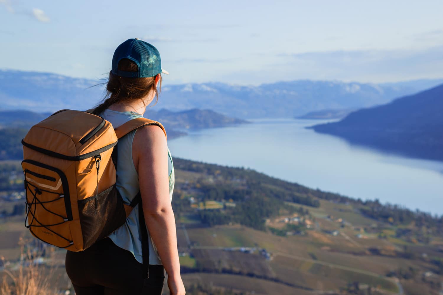 Woman standing on a mountain top wearing the EVERFUN soft cooler backpack.