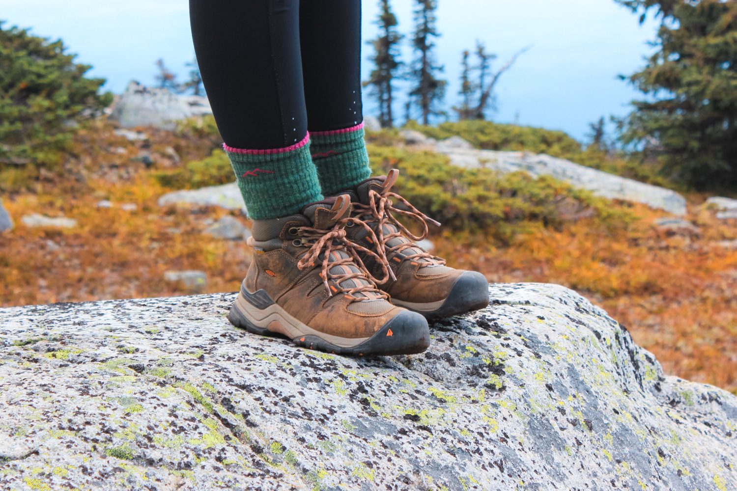 Closeup of hiking boots. Women standing on a rock.