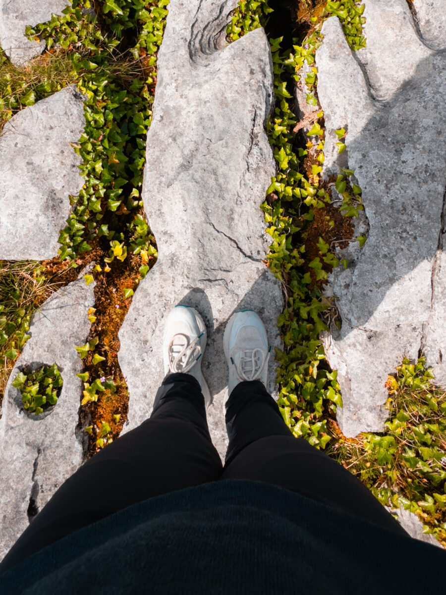 POV of feet standing on the limestone pavement of the Burren.