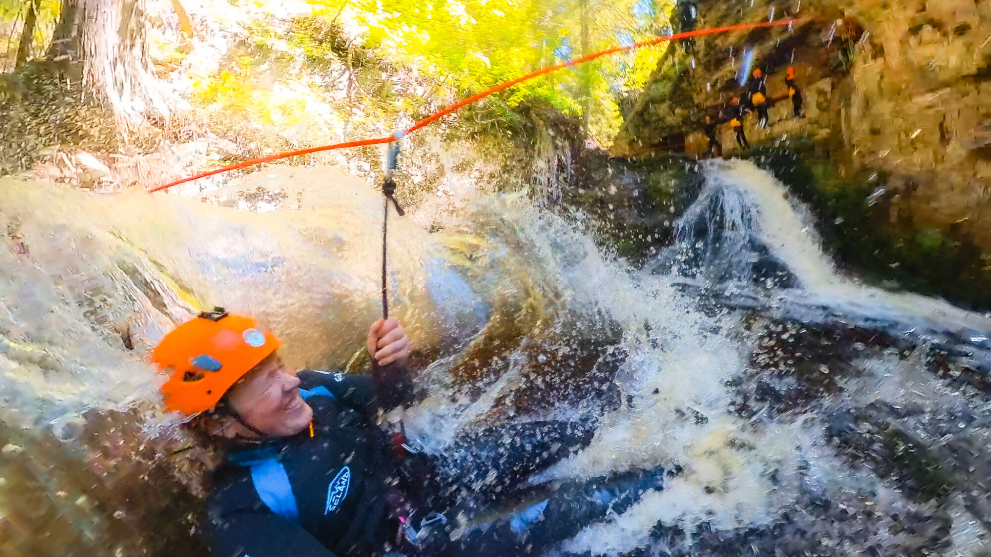 A woman lands in water after ziplining in a canyon