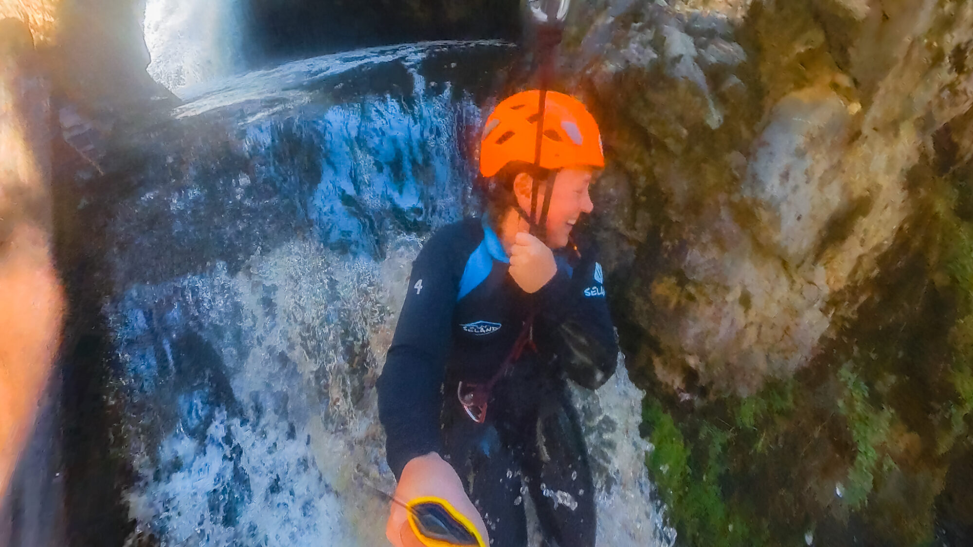 A woman ziplines over a large waterfall