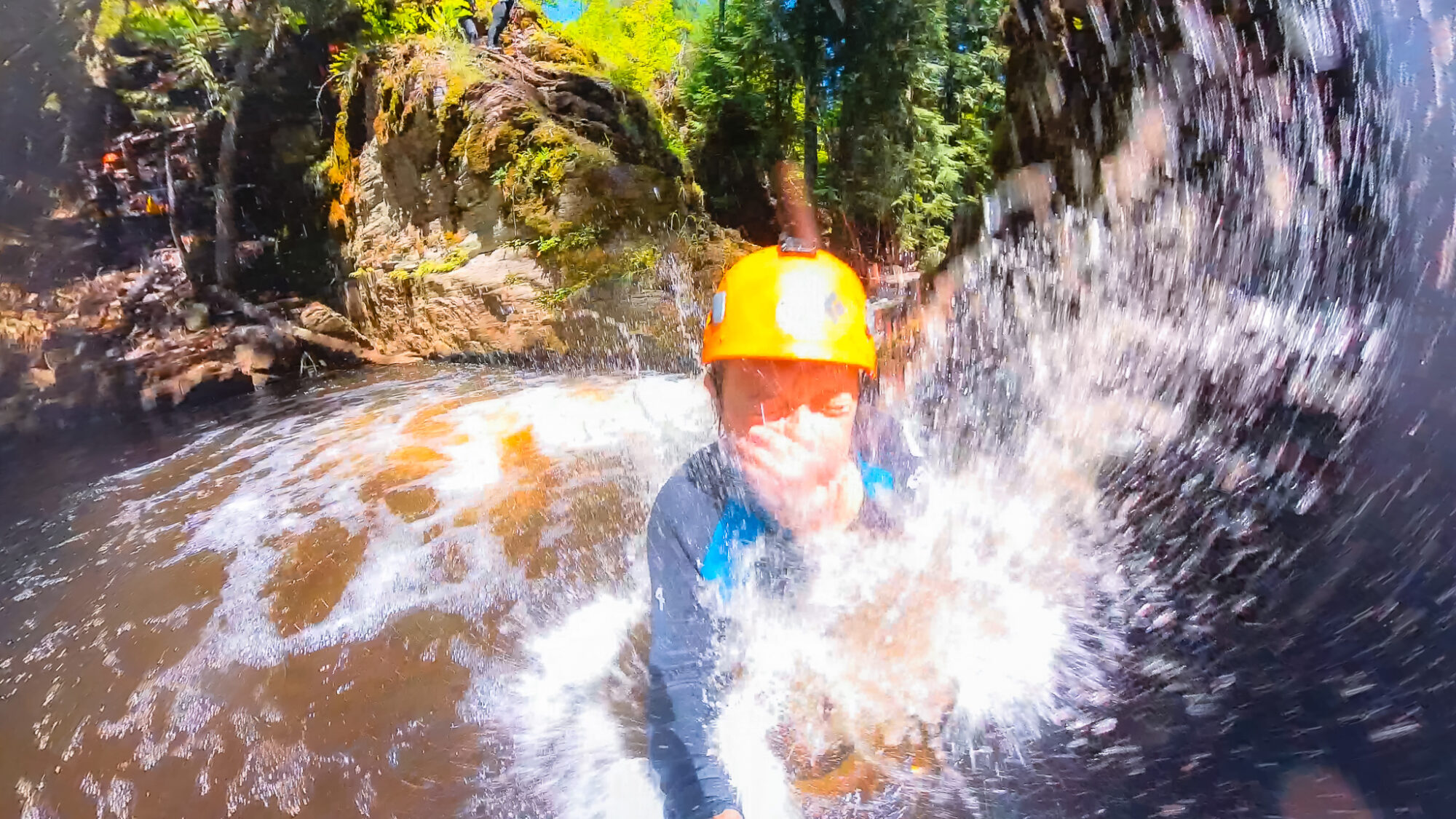 A woman jumps into a creek from the cliff