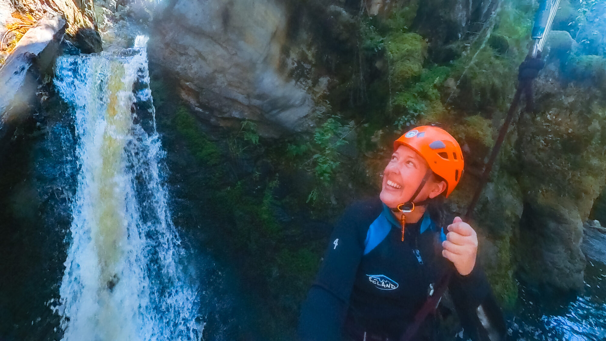 A woman looks back at a waterfall she ziplined down in an Okanagan canyon