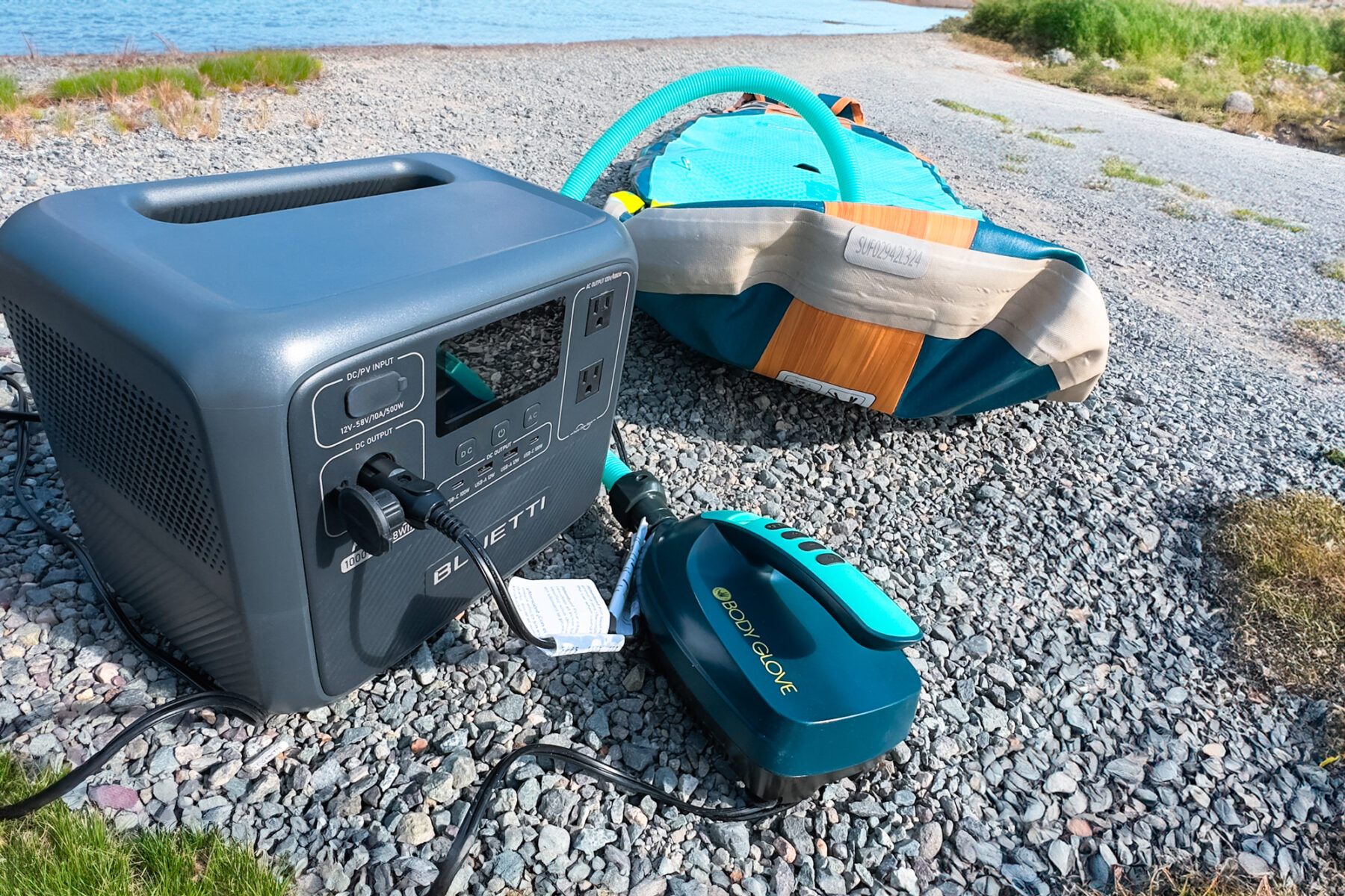 Bluetti AC70 powering a paddleboard pump and blowing up a paddleboard on the edge of a lake.