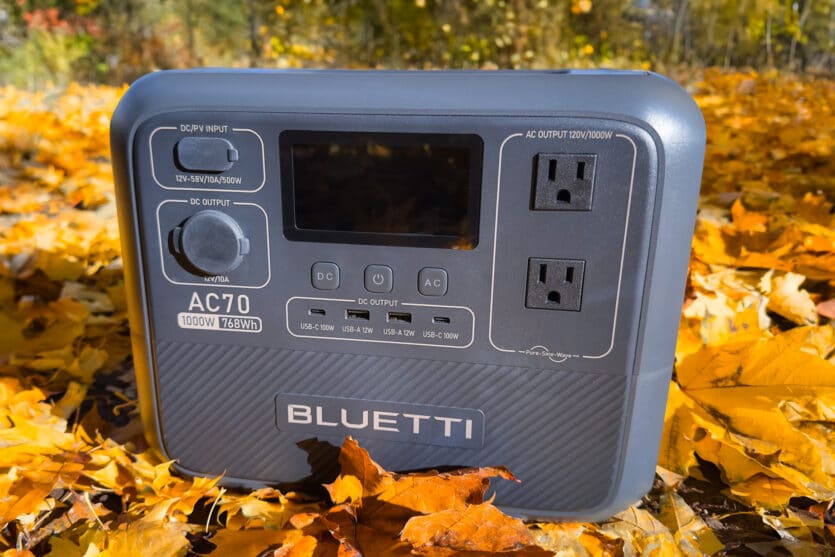 Bluetti AC70 1000W power station sitting in a bed of leaves.