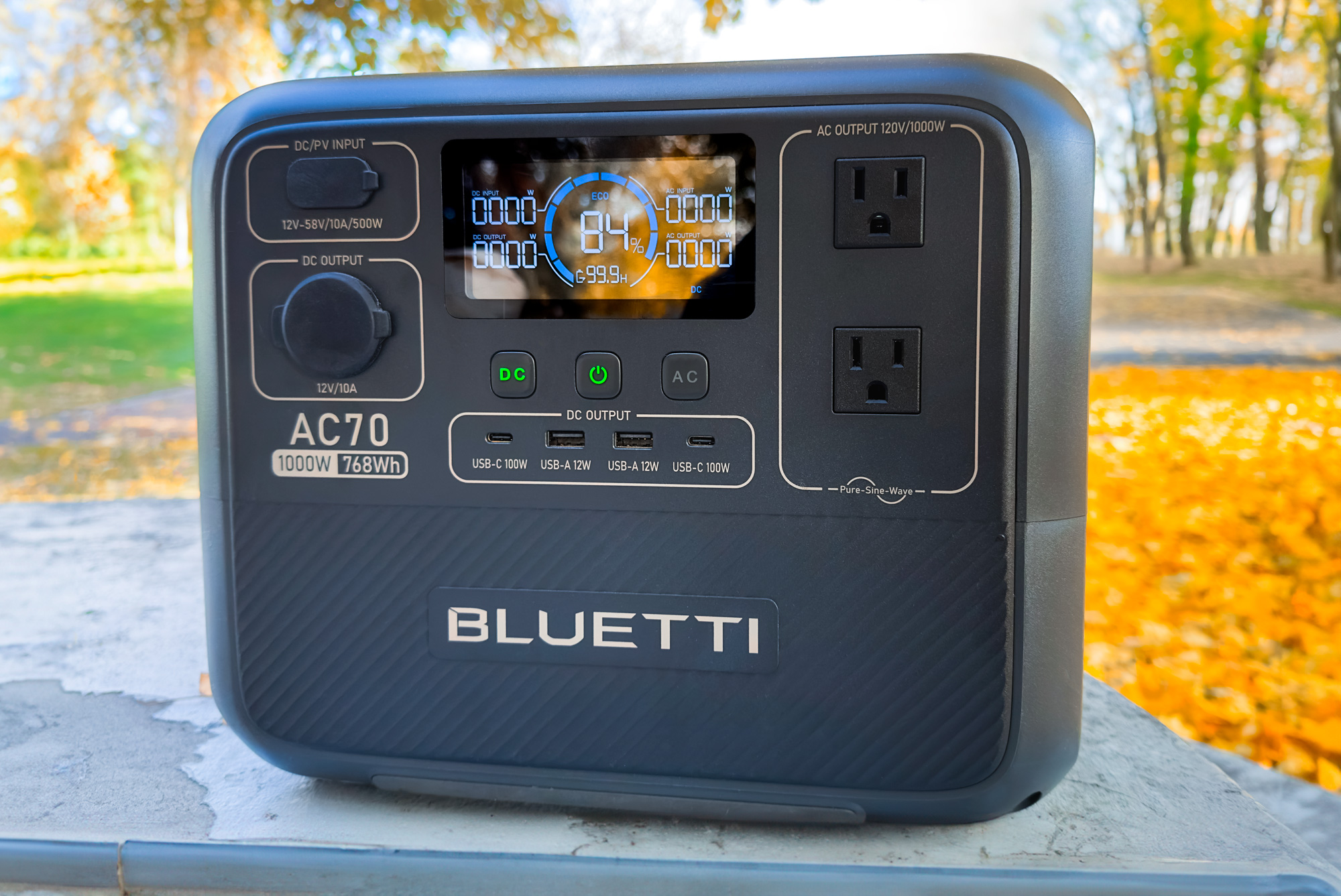 Close up of the Bluetti AC70 power station sitting on a picnic table at a campground.