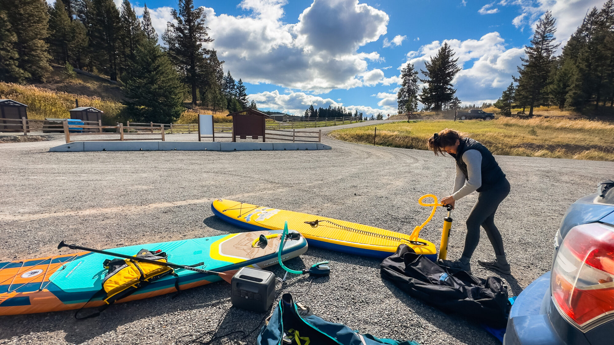 Bluetti AC70 blowing up a paddleboard while a friend pumps her paddleboard by hand.