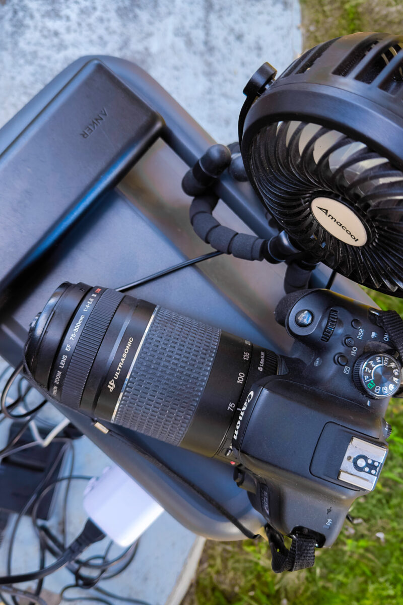 Top view of a mini fan, digital camera, and power bank sitting on the top of the power station.