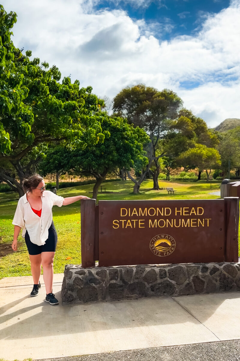 Woman stands at the Diamond Head State Monument sign.