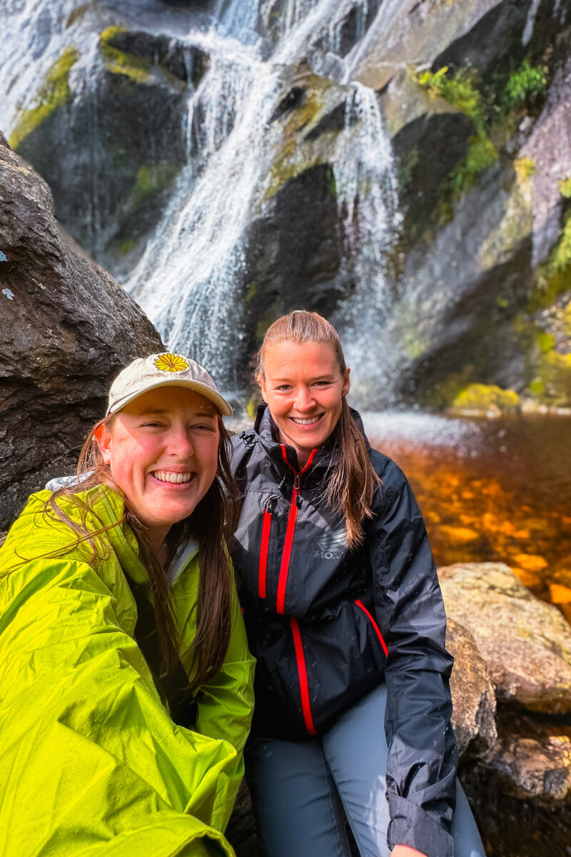 Selfie of two women at the base of a waterfall.