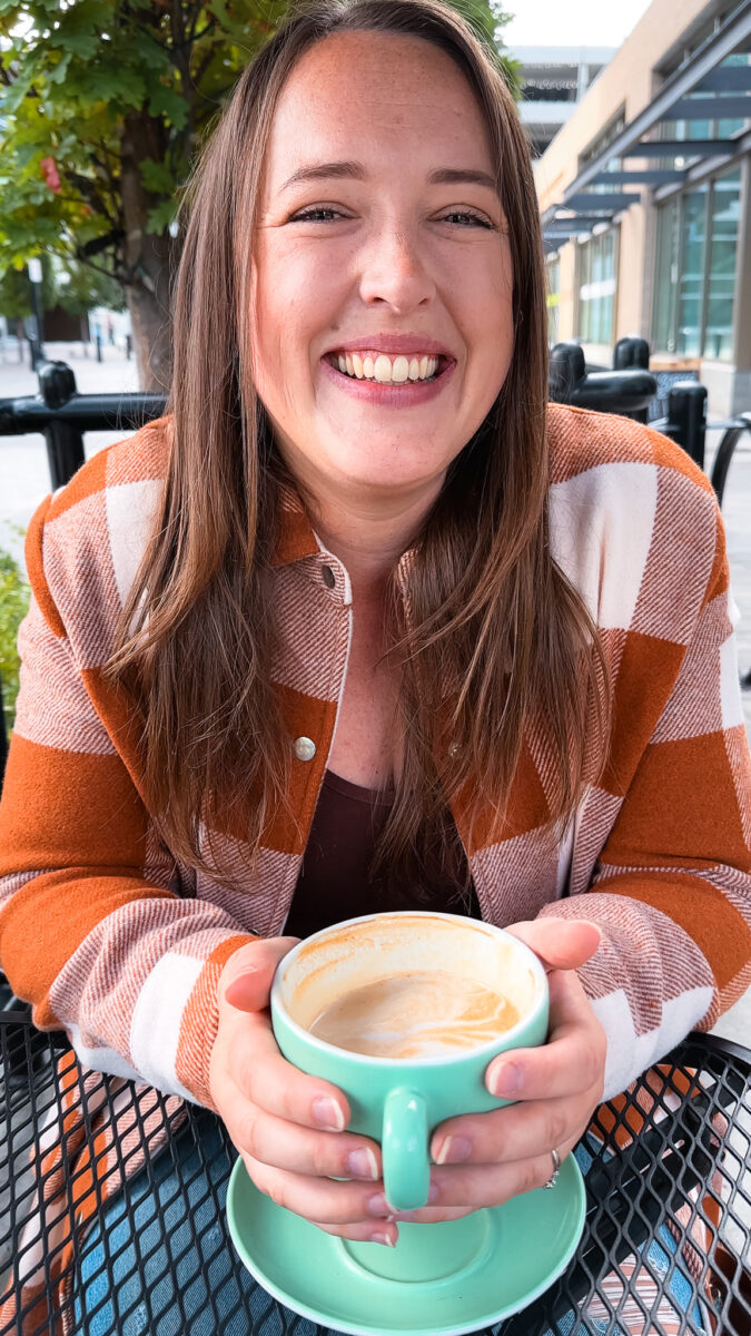 A woman smiling and holding a coffee cup.