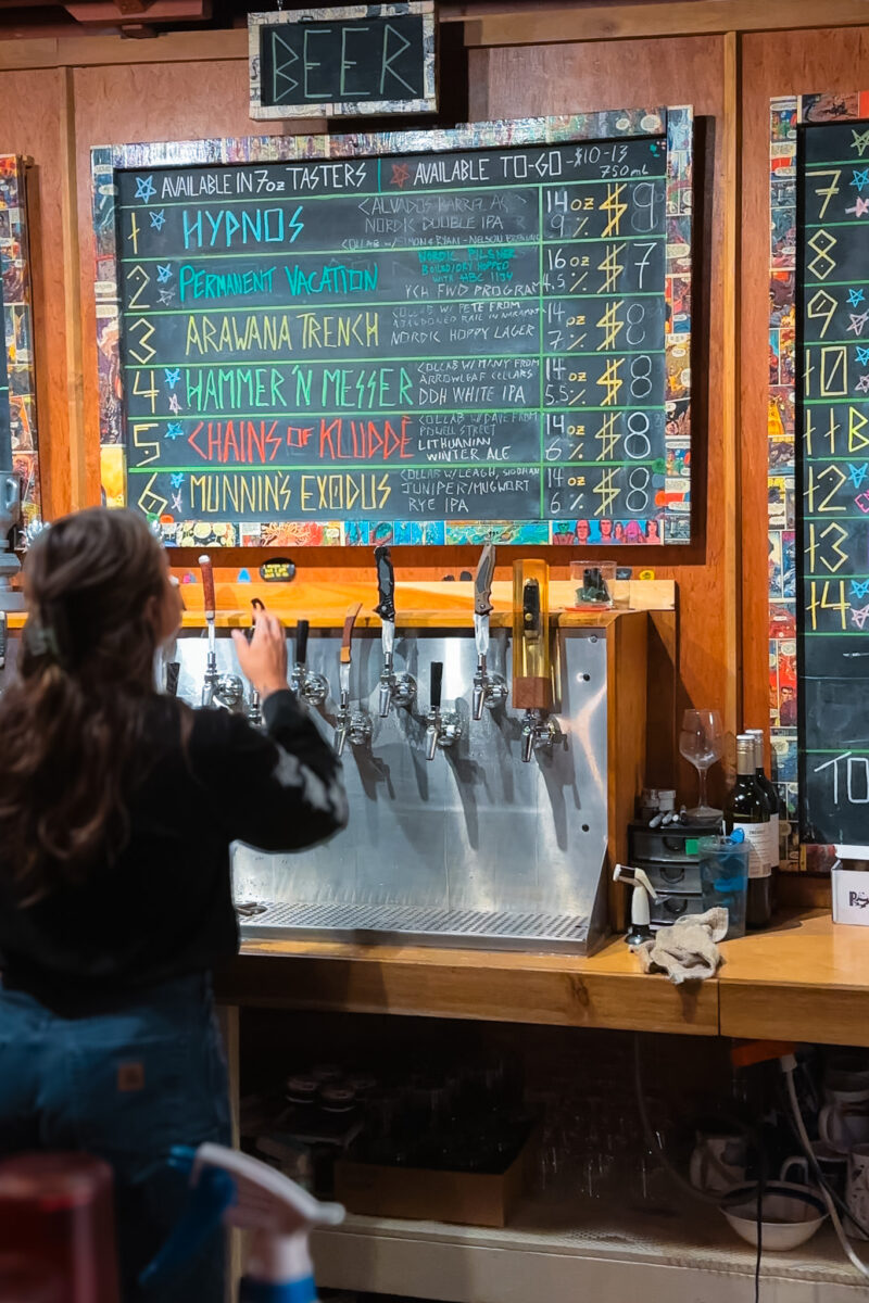 Bartender pours a beer with a menu behind her