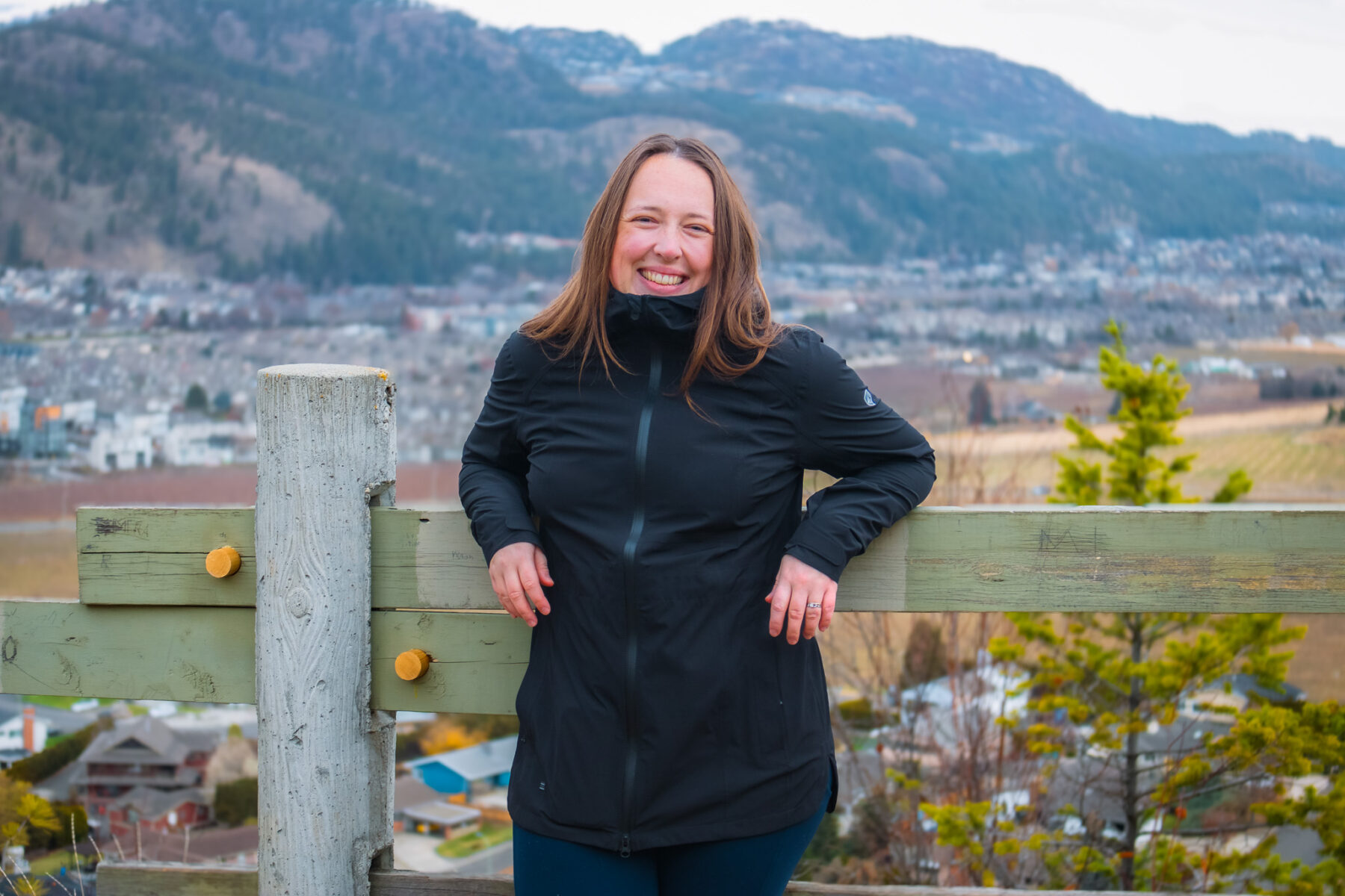 Woman leaning against a wooden fence.