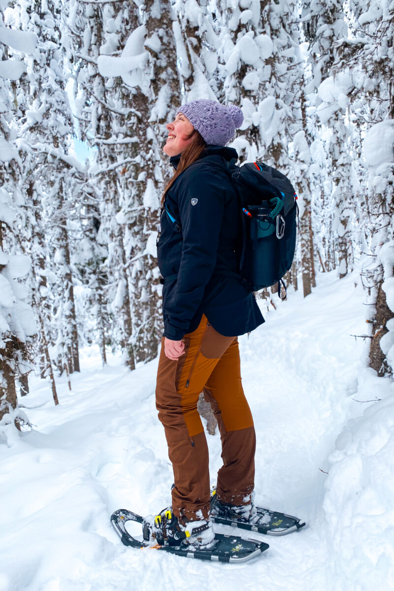 Woman in snowshoes. KUHL logo visible on the sleeve of the Voyagr rain jacket.