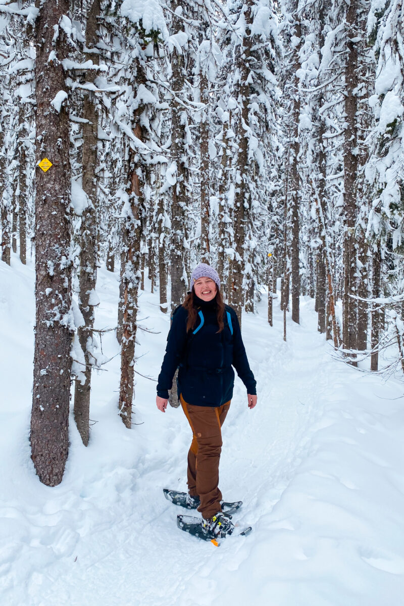 Woman in snowshoes on a snowy trail wearing a rain jacket as an outer layer.