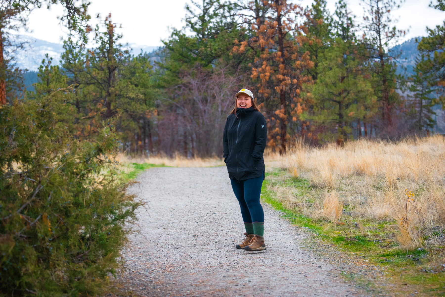 Woman laughing on a hiking trail on a rainy day.