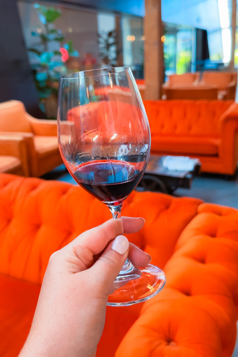 A closeup of red wine in front of bright orange couches.