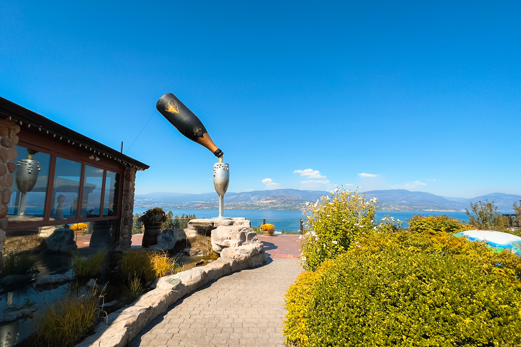 A huge wine bottle statue pouring into a glass overlooking Okanagan Lake at Summerhill Pyramid Winery in Kelowna.