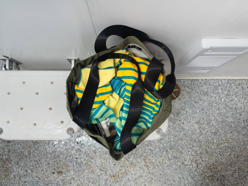 The Elements tote bag full of shower supplies in a campground shower stall