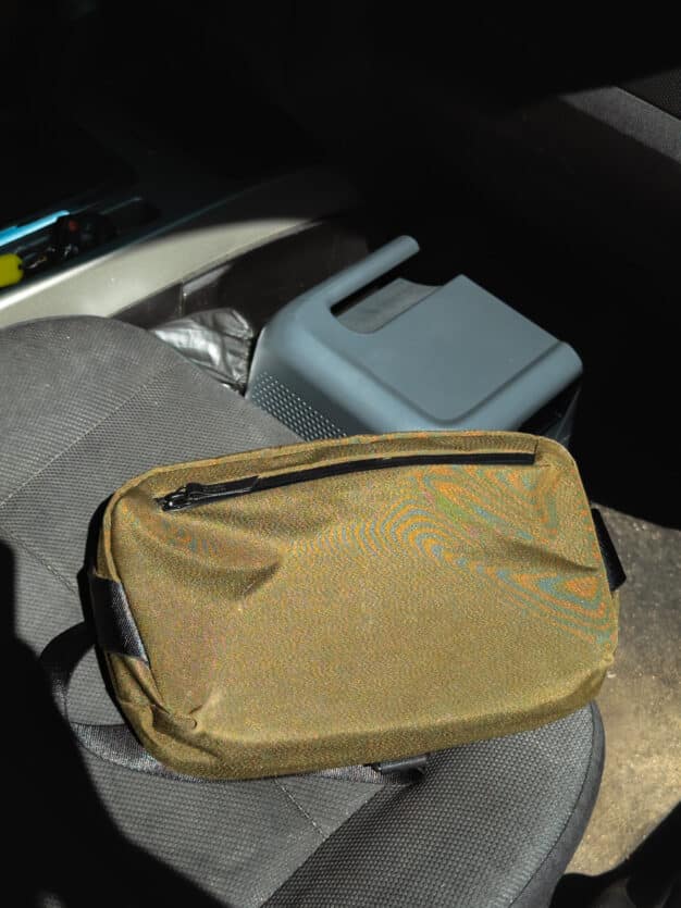 The ALPAKA Flight Sling sitting on a car seat, closup with a Bluetti power station in the background