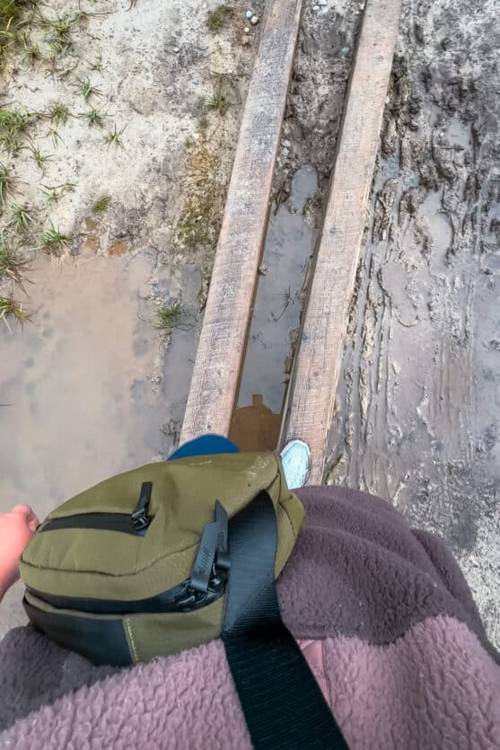 Woman wearing the Flight Sling on a muddy hiking trail