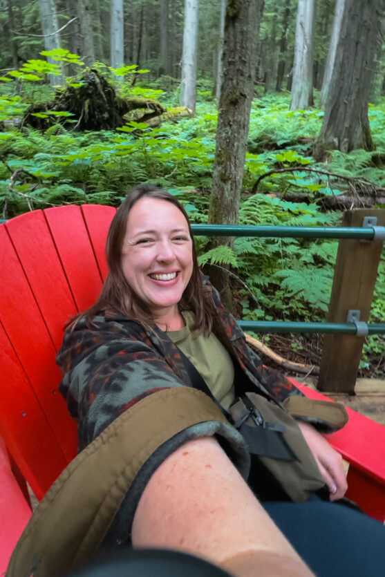 Woman wearing the ALPAKA flight sling, sitting on a red chair in Canada's national parks